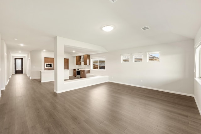 unfurnished living room featuring dark wood-type flooring and lofted ceiling