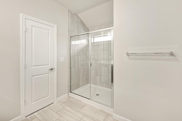 bathroom featuring tile patterned floors, lofted ceiling, and a shower with shower door