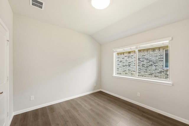 spare room with vaulted ceiling and hardwood / wood-style flooring