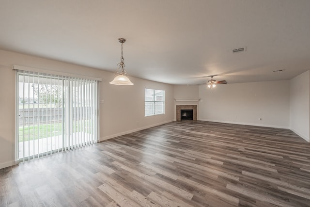 unfurnished living room with a tile fireplace, ceiling fan, and wood-type flooring