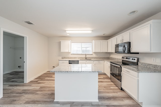 kitchen with white cabinetry, black appliances, light stone counters, and light hardwood / wood-style flooring