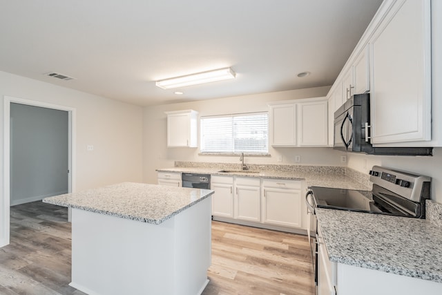 kitchen with stainless steel range with electric cooktop, white cabinetry, light hardwood / wood-style floors, and a kitchen island