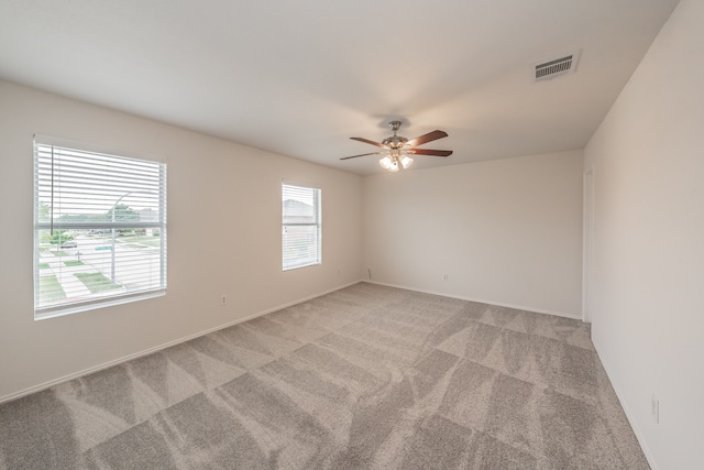 empty room featuring plenty of natural light, light carpet, and ceiling fan