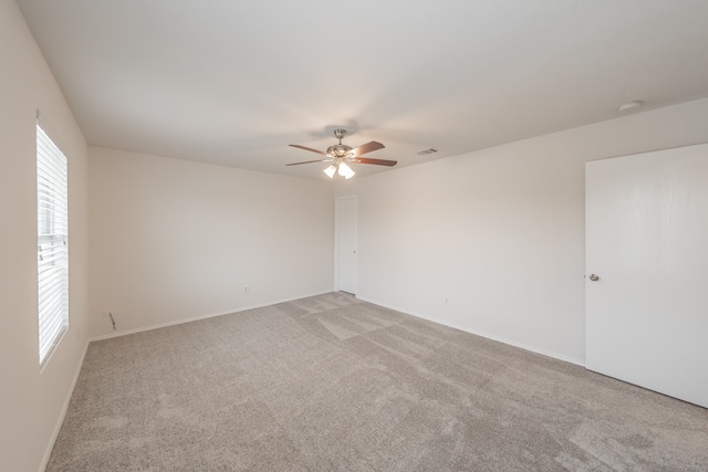 carpeted spare room with ceiling fan and plenty of natural light