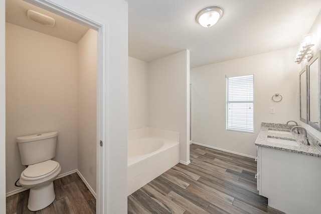 bathroom featuring hardwood / wood-style floors, double vanity, a bath, and toilet