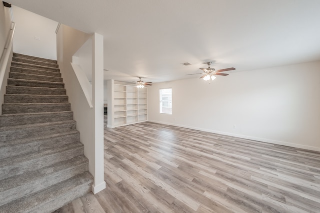 unfurnished living room featuring built in features, light wood-type flooring, and ceiling fan