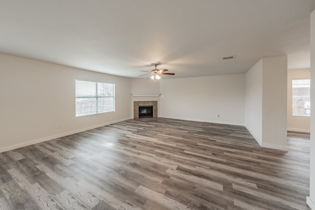 unfurnished living room with hardwood / wood-style flooring, a tiled fireplace, and ceiling fan