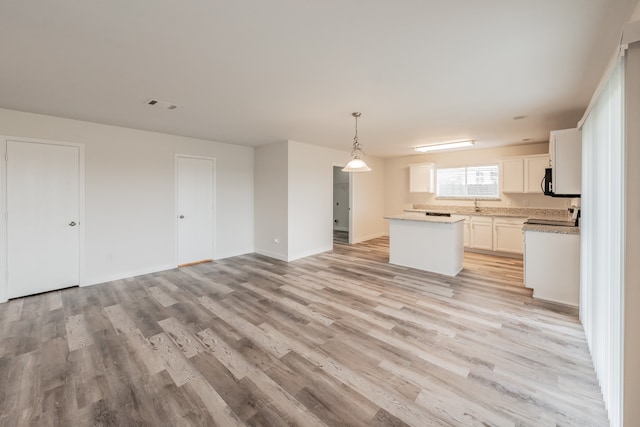 kitchen featuring sink, pendant lighting, light hardwood / wood-style floors, a kitchen island, and white cabinetry