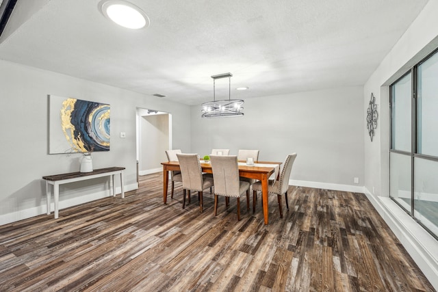 dining area featuring dark hardwood / wood-style flooring, a textured ceiling, and an inviting chandelier