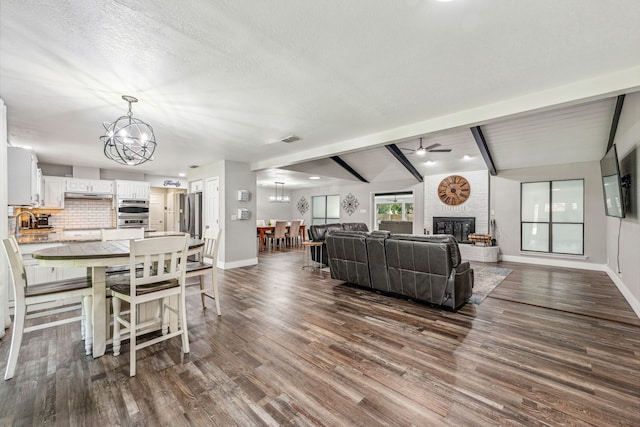 living room with a textured ceiling, a large fireplace, and dark hardwood / wood-style floors