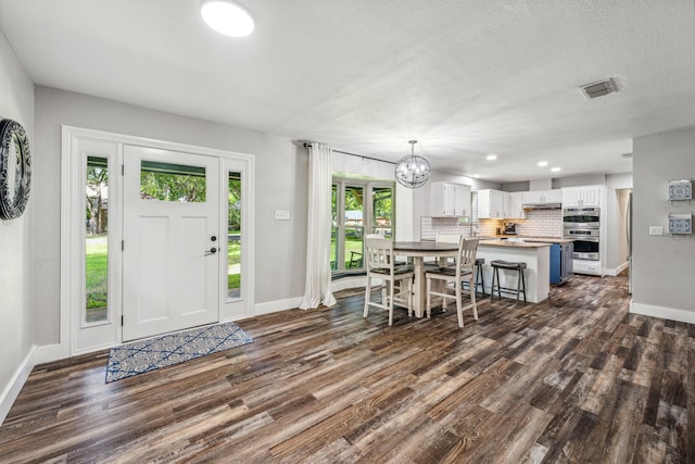 entrance foyer featuring a textured ceiling, dark hardwood / wood-style floors, and an inviting chandelier