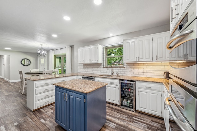 kitchen featuring white cabinets, a center island, sink, and wine cooler