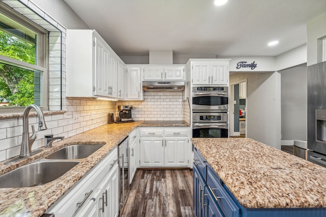 kitchen with white cabinets, sink, blue cabinetry, dark hardwood / wood-style flooring, and stainless steel double oven