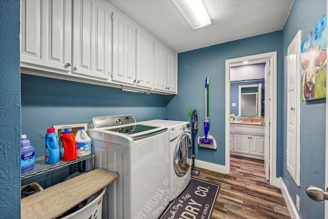 laundry room with cabinets, washer and clothes dryer, and dark wood-type flooring