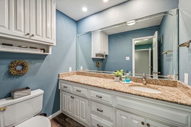 bathroom featuring vanity, wood-type flooring, and toilet