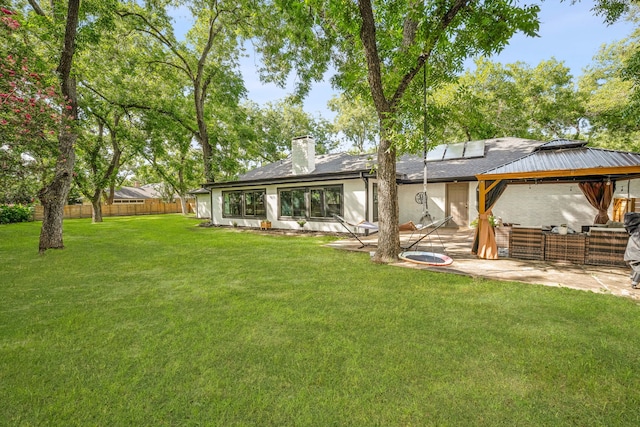 rear view of house with a gazebo, a patio area, and a lawn