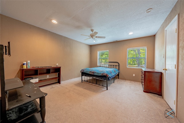 bedroom with a textured ceiling, carpet floors, and ceiling fan