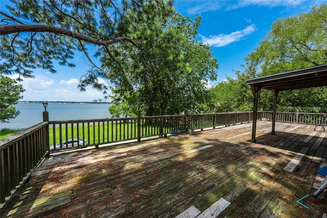 wooden terrace featuring a water view and a lawn