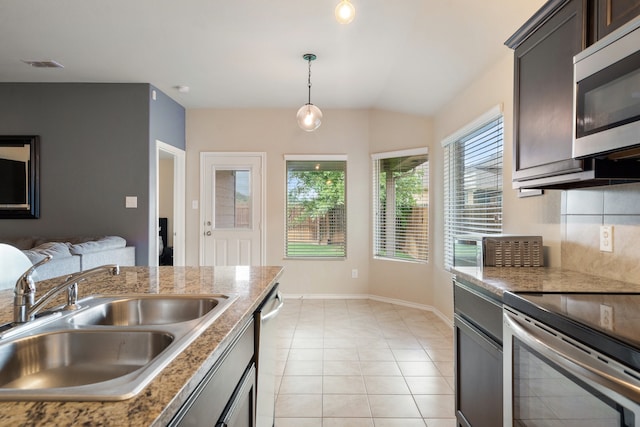 kitchen featuring decorative backsplash, light tile patterned floors, sink, decorative light fixtures, and stainless steel appliances