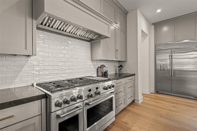 kitchen featuring premium range hood, gray cabinetry, backsplash, high end appliances, and light hardwood / wood-style flooring