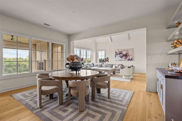 dining area with beam ceiling and light hardwood / wood-style flooring