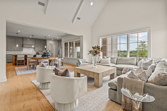 living room with beamed ceiling, light hardwood / wood-style flooring, and high vaulted ceiling