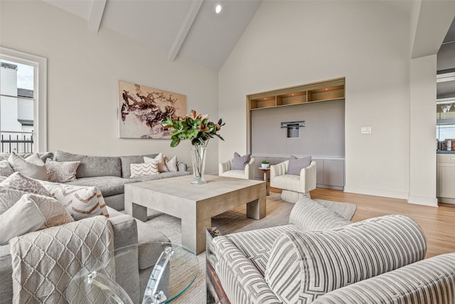 living room with light hardwood / wood-style floors, a wealth of natural light, beam ceiling, and high vaulted ceiling