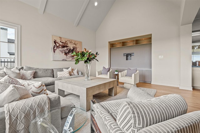 living room featuring beam ceiling, high vaulted ceiling, and light wood-type flooring