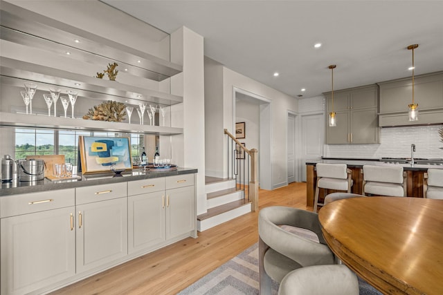 kitchen featuring hanging light fixtures, gray cabinetry, backsplash, and light wood-type flooring