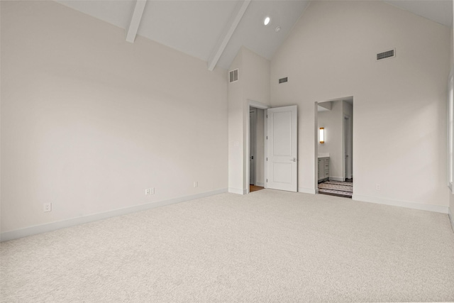 unfurnished bedroom with beamed ceiling, ensuite bathroom, light colored carpet, and high vaulted ceiling