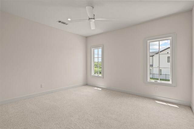 spare room featuring carpet, ceiling fan, and plenty of natural light