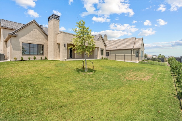 rear view of property featuring central AC and a yard