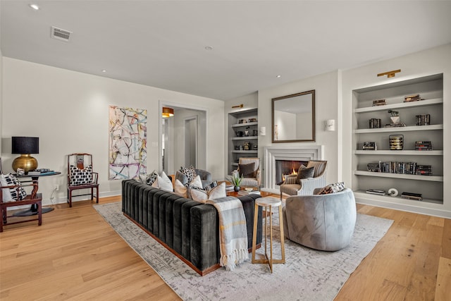 living room featuring built in features and light hardwood / wood-style flooring