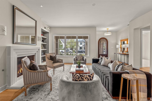 living room featuring built in shelves and light hardwood / wood-style flooring