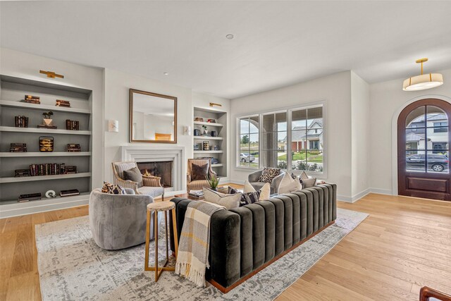 living room with built in features and light hardwood / wood-style flooring