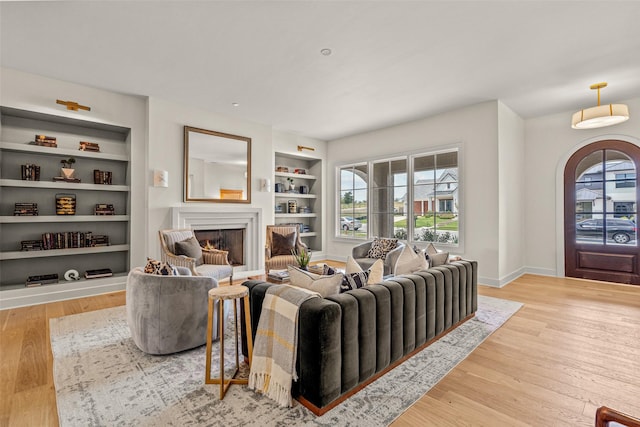 living room featuring built in shelves, a wealth of natural light, and light hardwood / wood-style floors