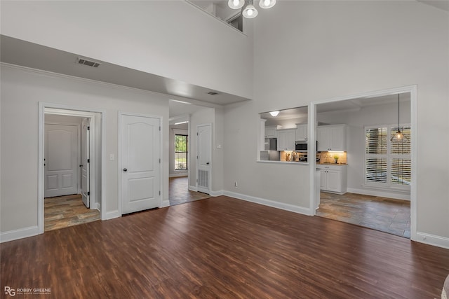 unfurnished living room with dark wood-type flooring and a high ceiling