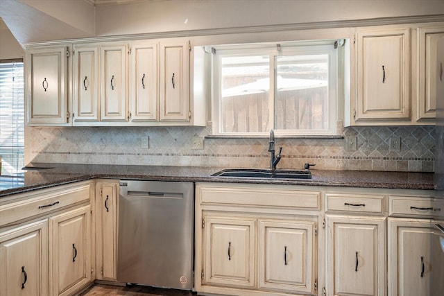 kitchen with dishwasher, sink, decorative backsplash, dark stone counters, and cream cabinets