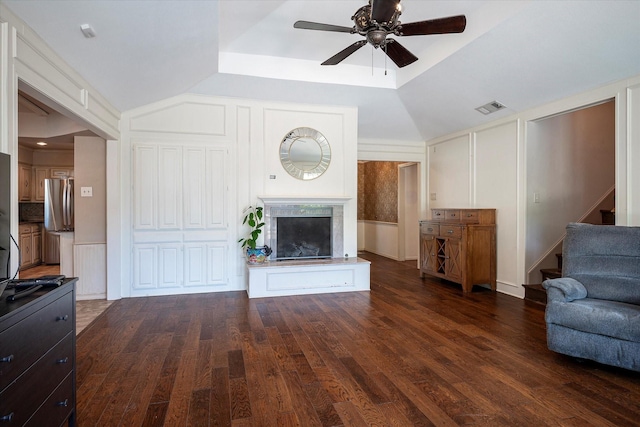 unfurnished living room with dark wood-type flooring, ceiling fan, a fireplace, and a raised ceiling