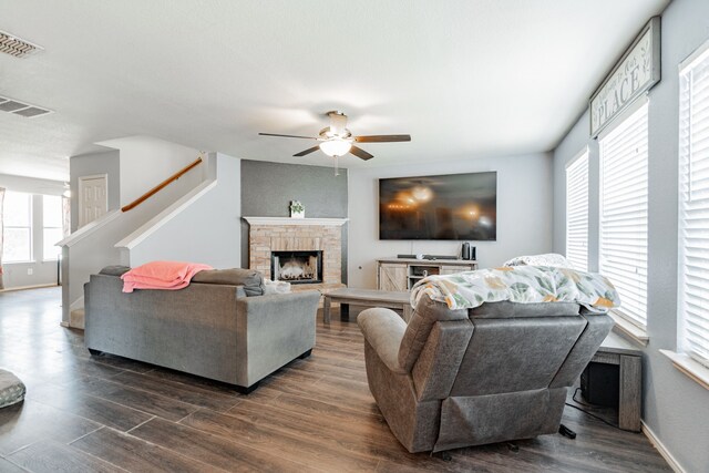 living room featuring wood-type flooring, a brick fireplace, and ceiling fan