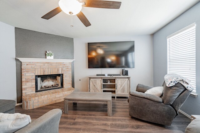 living room featuring ceiling fan, dark hardwood / wood-style floors, and a brick fireplace