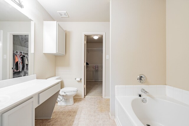 bathroom featuring vanity, toilet, tile patterned floors, and a tub