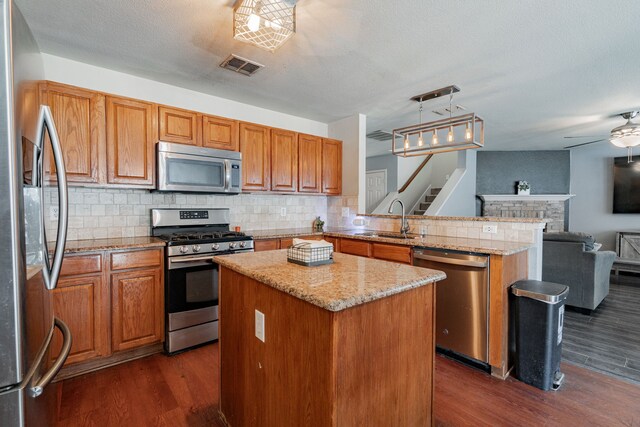 kitchen featuring tasteful backsplash, a center island, dark hardwood / wood-style flooring, ceiling fan, and appliances with stainless steel finishes