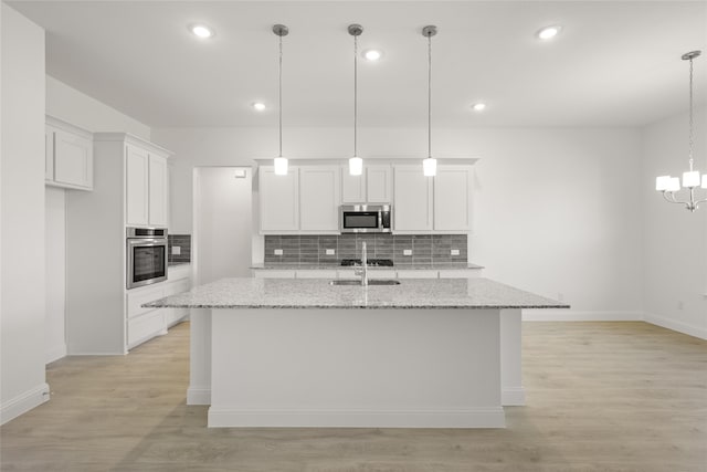 kitchen with white cabinets, a kitchen island with sink, stainless steel appliances, and backsplash