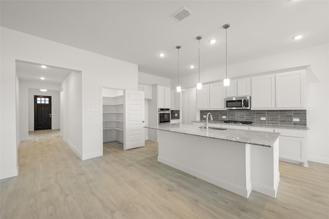 kitchen featuring light hardwood / wood-style flooring, white cabinets, a kitchen island with sink, and stainless steel appliances