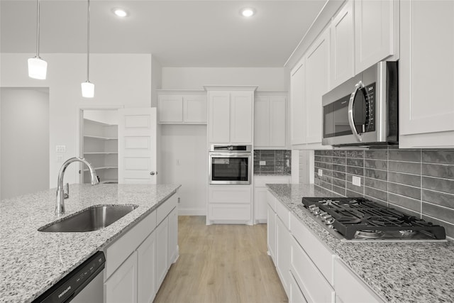 kitchen featuring sink, light stone countertops, stainless steel appliances, and white cabinets