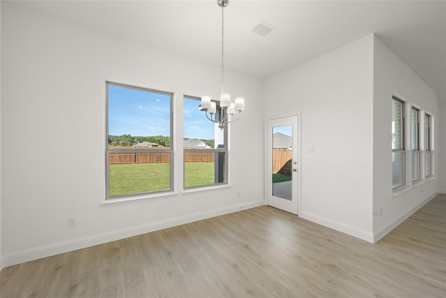 unfurnished dining area featuring light hardwood / wood-style flooring and an inviting chandelier