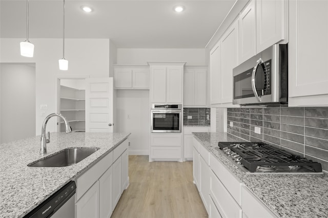 kitchen with sink, stainless steel appliances, white cabinets, and light stone countertops