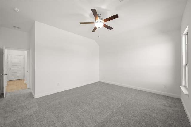 empty room featuring vaulted ceiling, light colored carpet, and ceiling fan