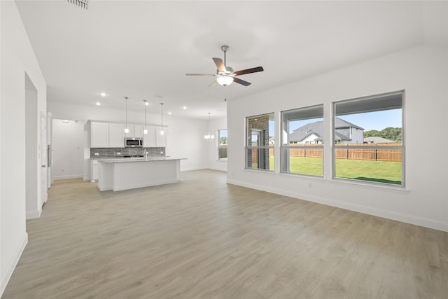 unfurnished living room featuring light hardwood / wood-style flooring, sink, and ceiling fan